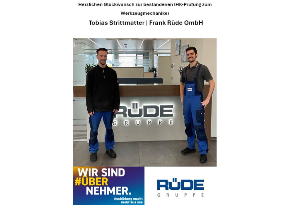 Ausbilder und Auszubildender stehen gemeinsam am Empfangstresen der Rüde Gruppe und freuen sich über die erfolgreich bestandene Ausbildung