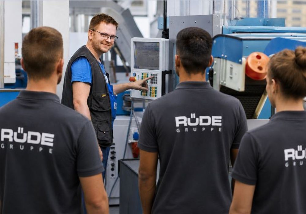 Stellvertretender Produktionsleiter instruiert seine Mitarbeitenden wie die Produktionsmaschine eingestellt werden soll.