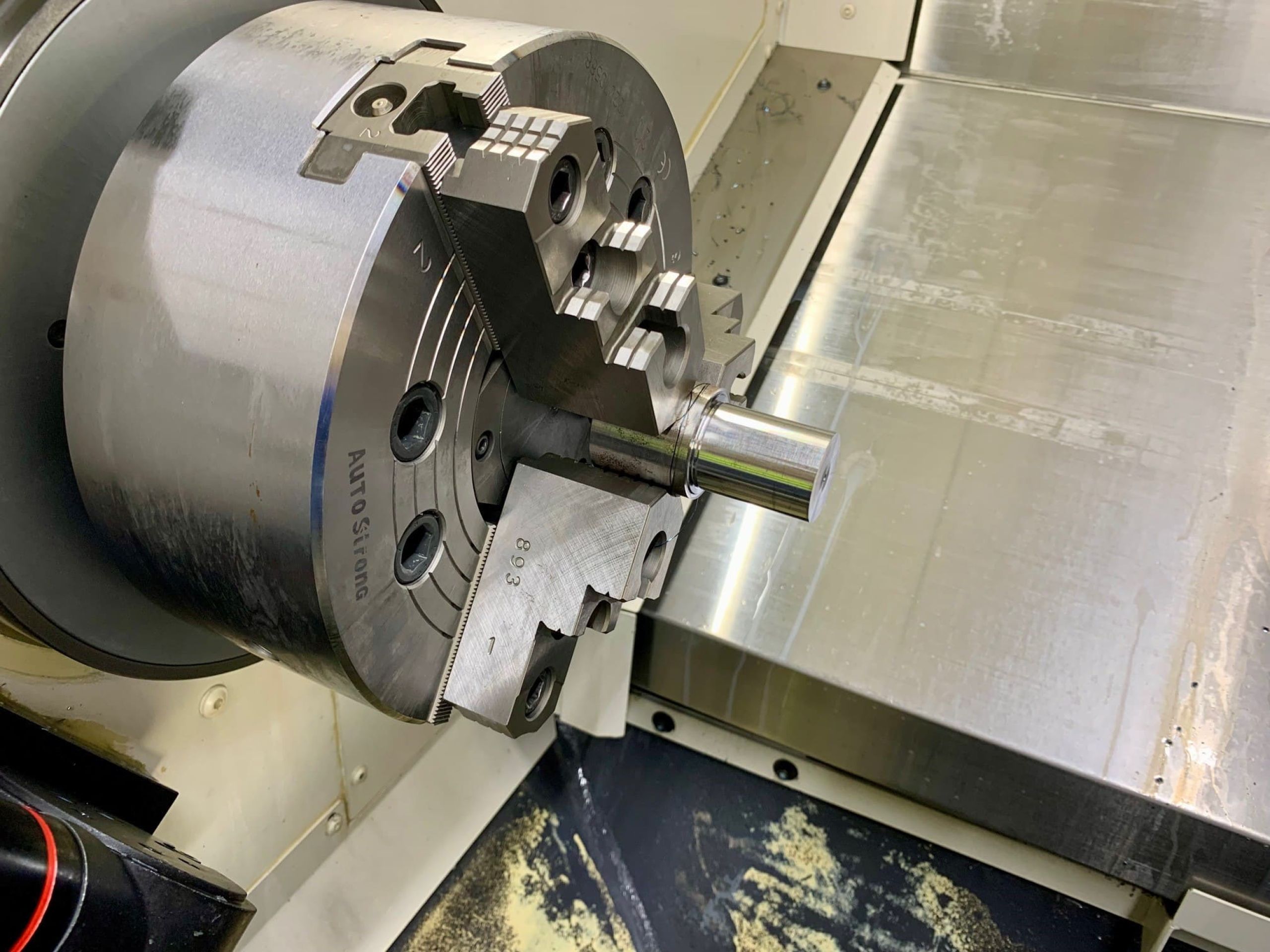 CNC-Drehen eines Präzisionsdrehteils aus Stahl im Dreibackenfutter einer CNC-Drehmaschine